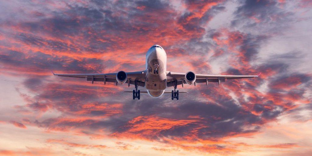 降落的飞机. 风景与客机在蓝天与红色中飞翔, 日落时紫色和橙色的云. 旅游的背景. 客机. 商用飞机. 私CQ9电子飞机